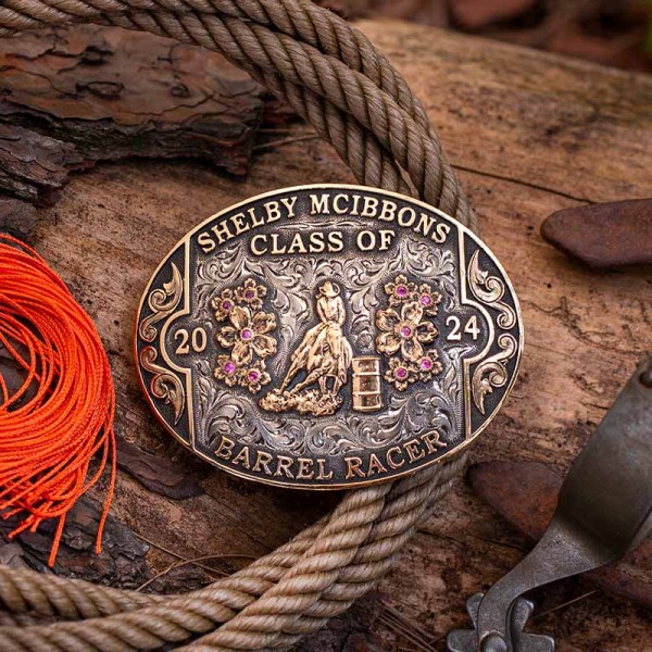 A custom rodeo belt buckle with personalized name featuring a golden bronze barrel racer figure and flowers 